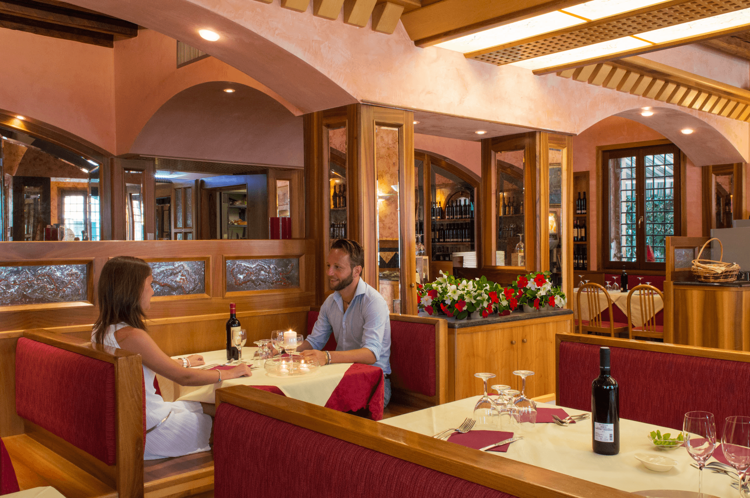 Coppia a cena in un ristorante elegante con arredi in legno e luci soffuse.