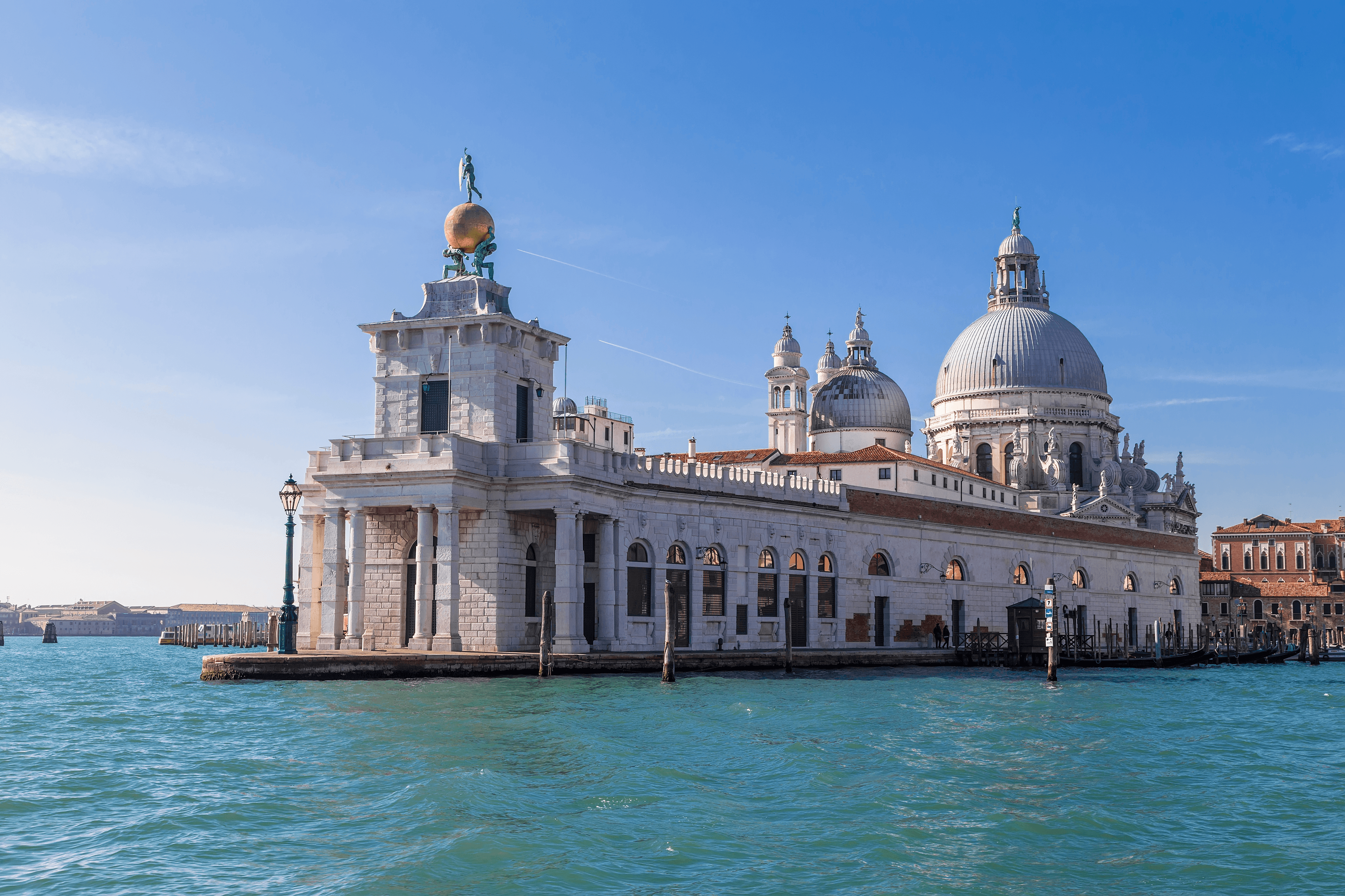 Punta della Dogana e Basilica di Santa Maria della Salute sotto un cielo azzurro limpido.